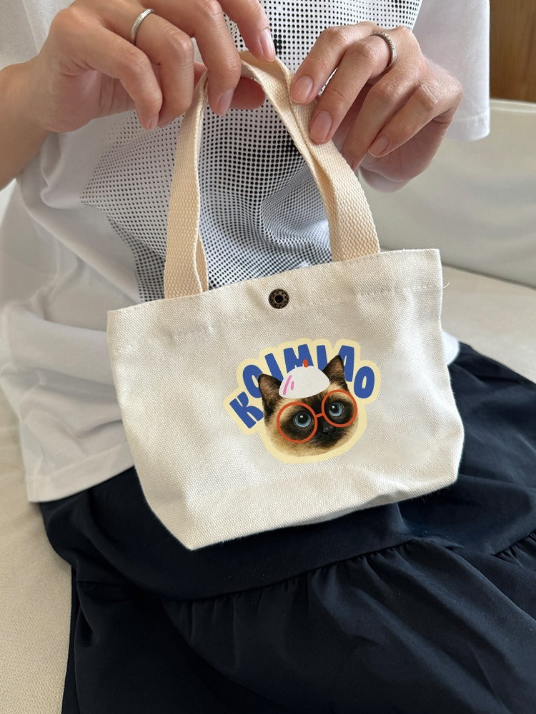 Small tote bag with a dog graphic and text held by a person