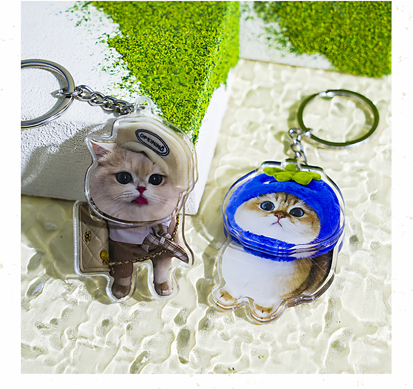 Two cat-themed keychains with helmets on a textured surface.