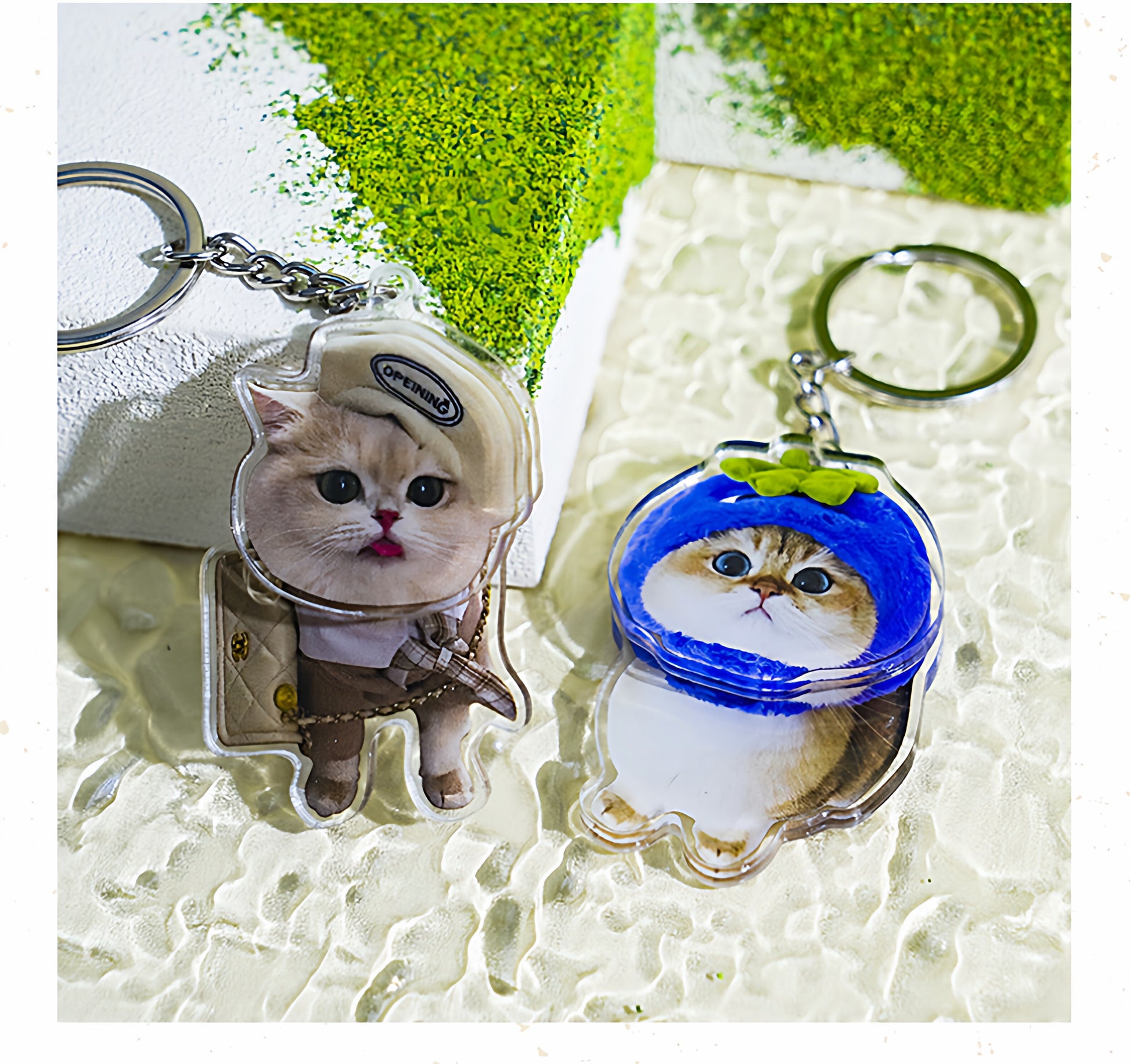 Two cat-themed keychains with helmets on a textured surface.